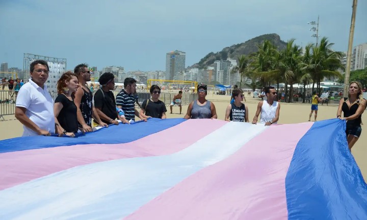 pessoas trans segurando uma bandeira rosa e azul